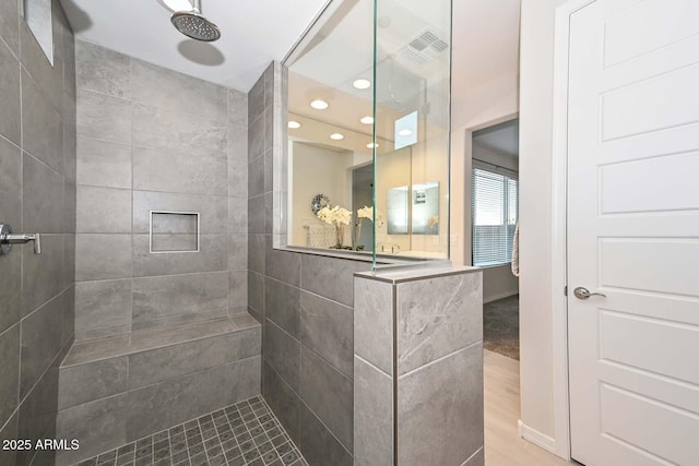 bathroom featuring hardwood / wood-style flooring and a tile shower