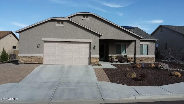 view of front of house with solar panels, stone siding, concrete driveway, and stucco siding