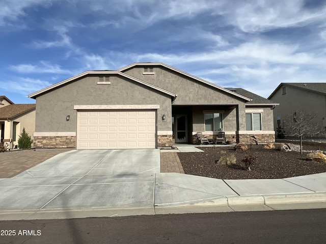 view of front of property featuring a garage, stone siding, concrete driveway, and stucco siding