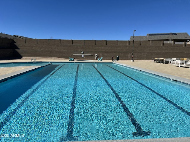 community pool with a fenced backyard and a patio