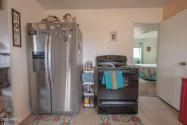 kitchen with light tile patterned flooring, stainless steel fridge, and black range with electric stovetop