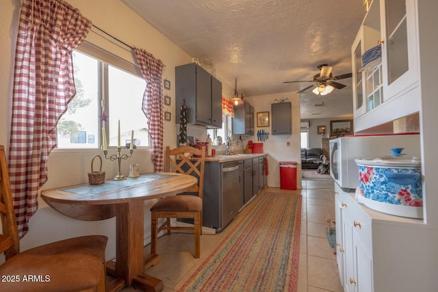 kitchen featuring light tile patterned floors, gray cabinets, ceiling fan, a textured ceiling, and stainless steel dishwasher