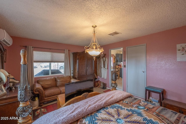 bedroom featuring an AC wall unit and a textured ceiling