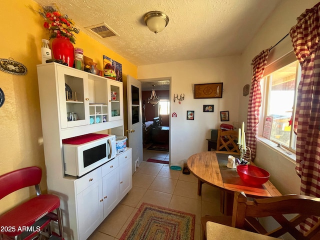 kitchen with light tile patterned floors, white cabinets, and a textured ceiling