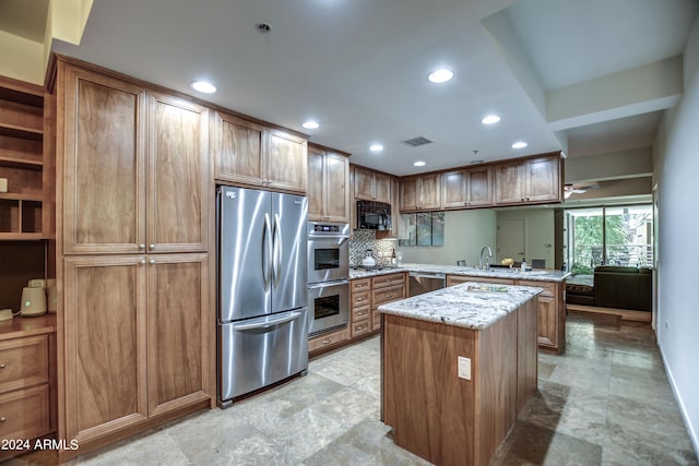 kitchen with kitchen peninsula, light stone countertops, stainless steel appliances, a center island, and sink