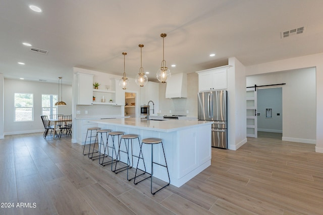 3939 S Veronica Ln, Gold Canyon, AZ 85118 - kitchen featuring open shelves, a sink, a barn door, visible vents, and freestanding refrigerator