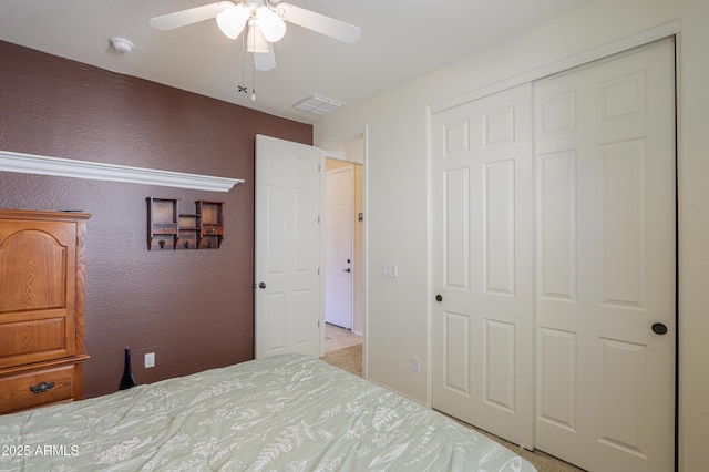 unfurnished bedroom with a textured wall, a closet, visible vents, and a ceiling fan