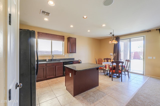 kitchen with a sink, a kitchen island, visible vents, black appliances, and dark countertops