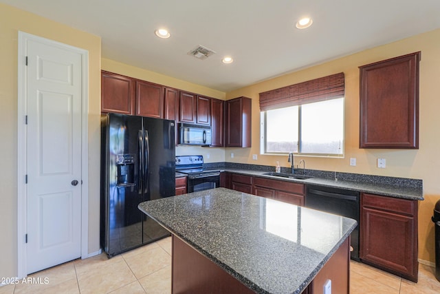 kitchen with a sink, a kitchen island, visible vents, black appliances, and dark stone countertops