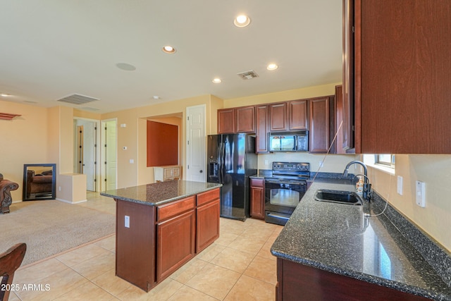 kitchen with a sink, a kitchen island, visible vents, black appliances, and dark stone countertops