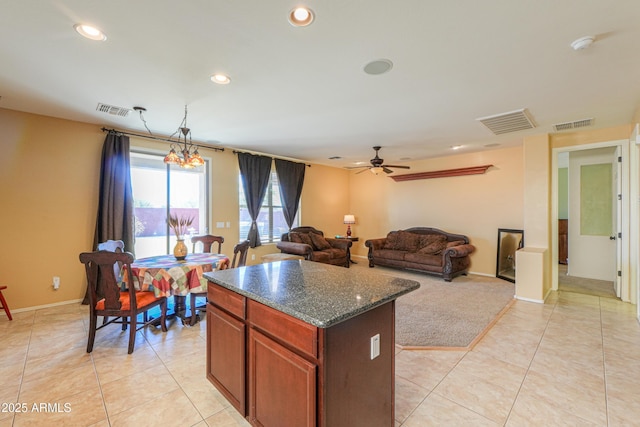 kitchen featuring light tile patterned floors, visible vents, dark stone counters, a kitchen island, and open floor plan