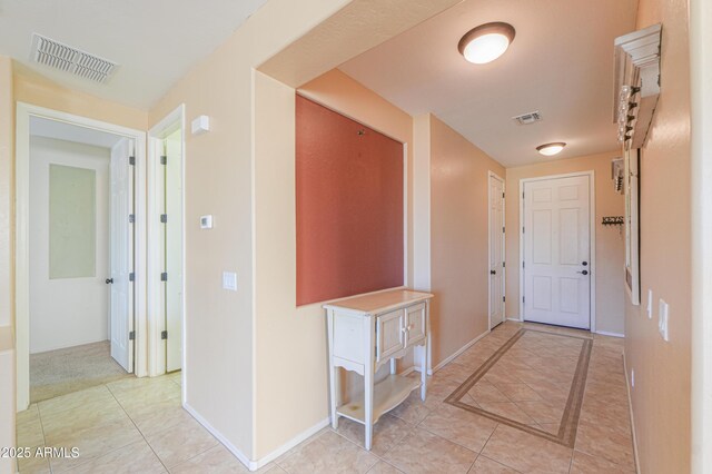 hall with light tile patterned flooring, visible vents, and baseboards