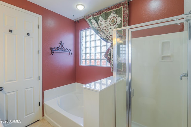 bathroom with a shower stall, a bath, and a textured wall