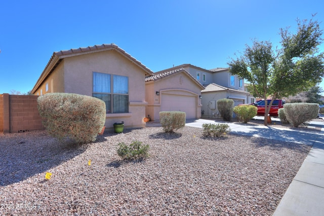 view of front of home featuring concrete driveway, a tiled roof, an attached garage, fence, and stucco siding