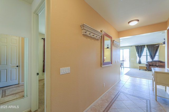 hall with light tile patterned flooring and baseboards