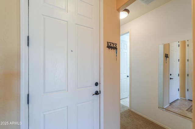 corridor with baseboards and light colored carpet