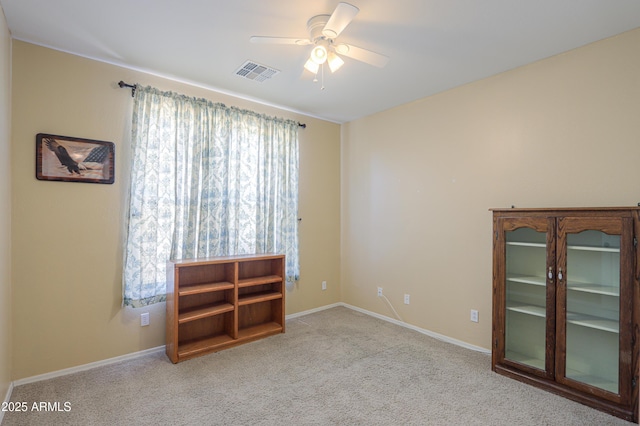 spare room with light carpet, baseboards, visible vents, and a ceiling fan