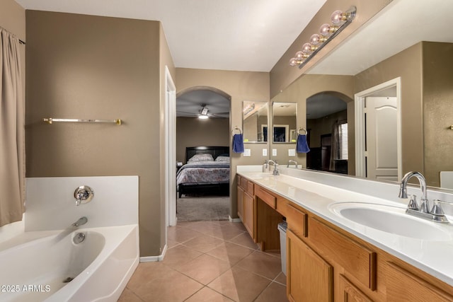 ensuite bathroom with a sink, tile patterned flooring, ceiling fan, and a garden tub