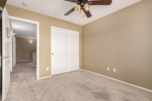 unfurnished bedroom featuring baseboards, ceiling fan, carpet, and a closet