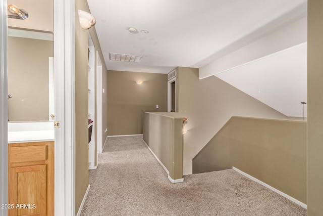 hallway featuring visible vents, baseboards, an upstairs landing, and carpet