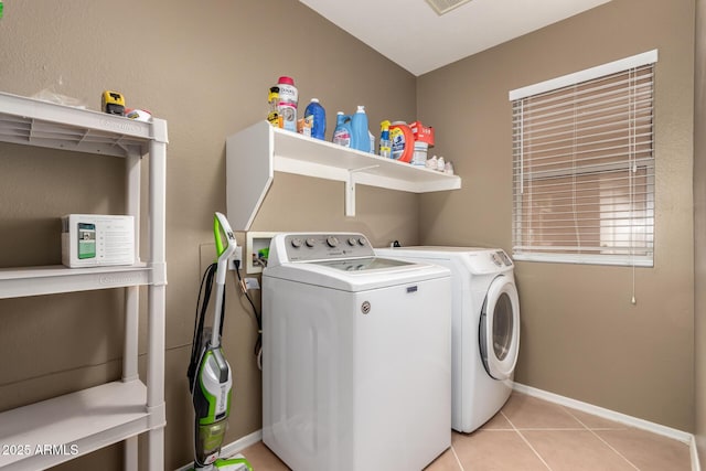 washroom with independent washer and dryer, light tile patterned floors, laundry area, and baseboards
