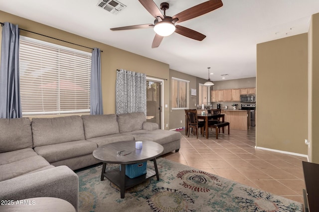 living area featuring light tile patterned flooring, a ceiling fan, visible vents, and baseboards