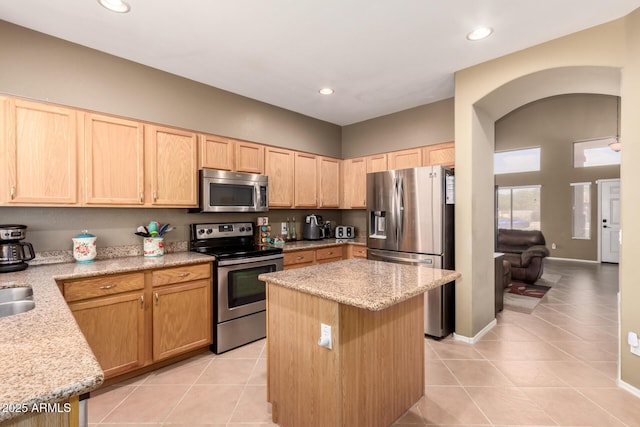 kitchen featuring a center island, appliances with stainless steel finishes, light tile patterned flooring, and light brown cabinets