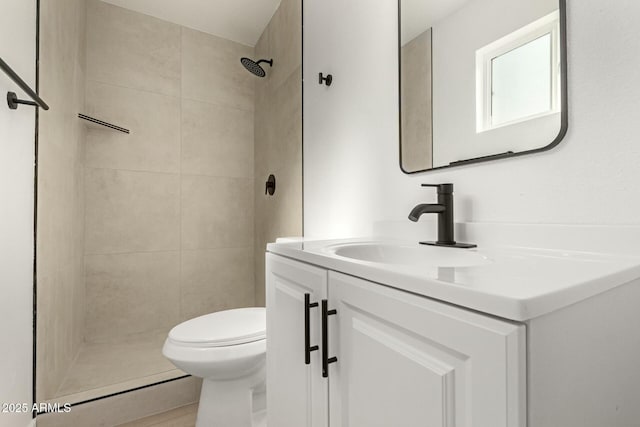 bathroom with tiled shower, vanity, and toilet