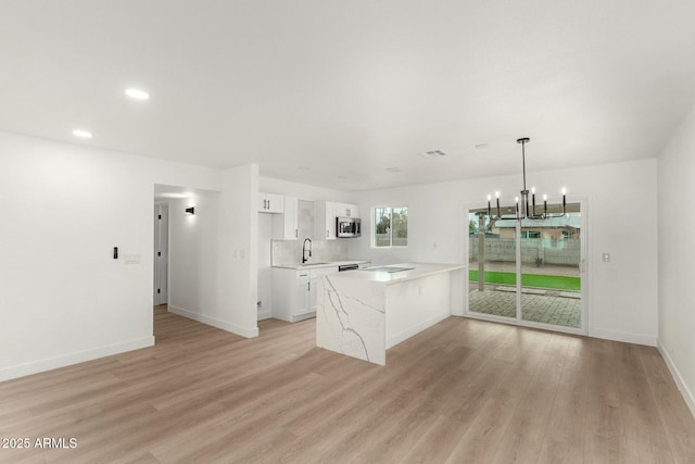 kitchen featuring hanging light fixtures, light hardwood / wood-style flooring, kitchen peninsula, and white cabinets