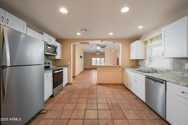 kitchen with sink, appliances with stainless steel finishes, white cabinetry, tasteful backsplash, and kitchen peninsula