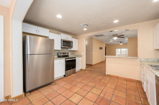 kitchen with white cabinetry, appliances with stainless steel finishes, kitchen peninsula, ceiling fan, and backsplash