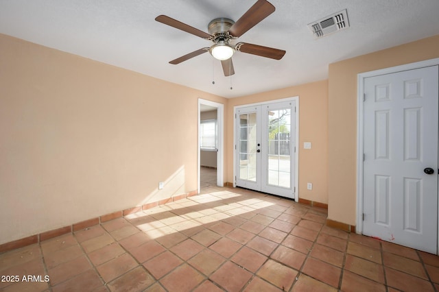 tiled empty room featuring french doors and ceiling fan