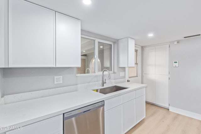 kitchen featuring white cabinetry, sink, stainless steel dishwasher, and light hardwood / wood-style floors