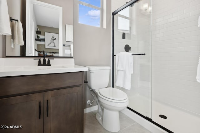 bathroom featuring tile patterned flooring, vanity, toilet, and a shower with shower door