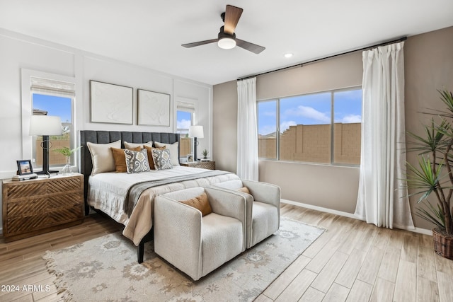 bedroom with light wood-type flooring, multiple windows, and baseboards