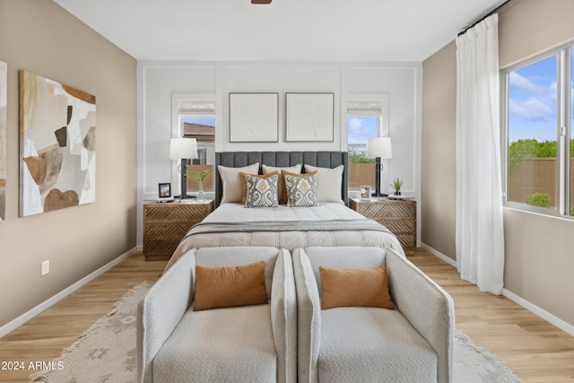 bedroom with light wood-type flooring, multiple windows, and baseboards