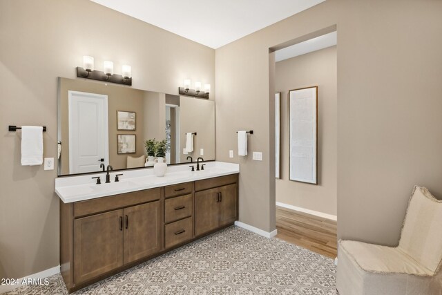 bathroom featuring double vanity, baseboards, and a sink