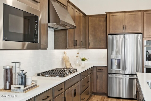 kitchen featuring under cabinet range hood, backsplash, stainless steel appliances, and light countertops