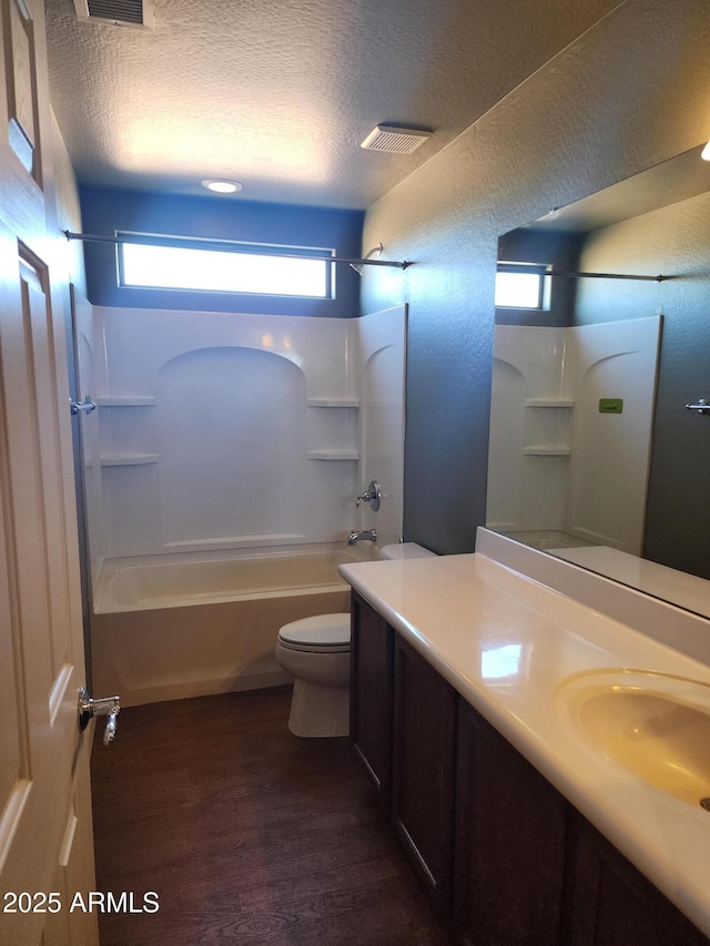 full bathroom with shower / bath combination, wood-type flooring, a textured ceiling, and toilet