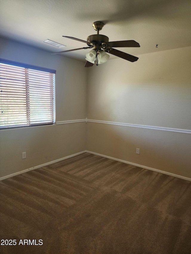 empty room with ceiling fan and dark colored carpet