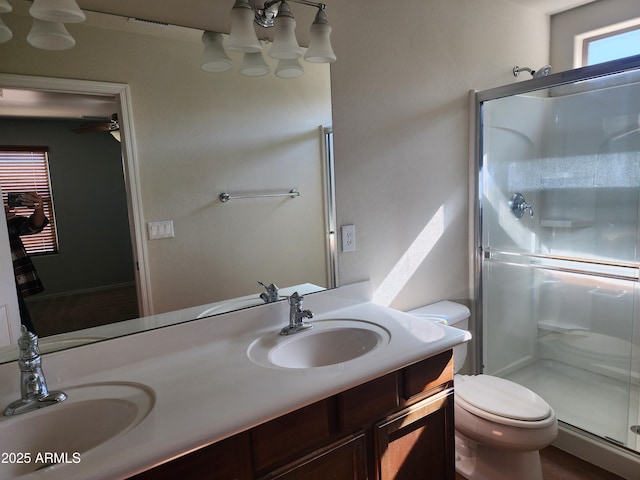 bathroom featuring vanity, a shower with door, and toilet