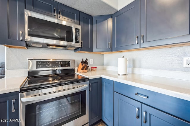 kitchen featuring a textured ceiling, blue cabinetry, appliances with stainless steel finishes, and tasteful backsplash