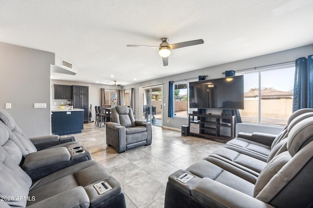 living room with ceiling fan, a textured ceiling, and a wealth of natural light