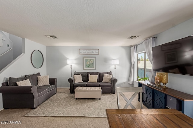 living area featuring carpet flooring, visible vents, and a textured ceiling