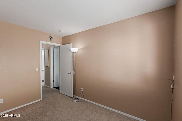 carpeted empty room featuring baseboards