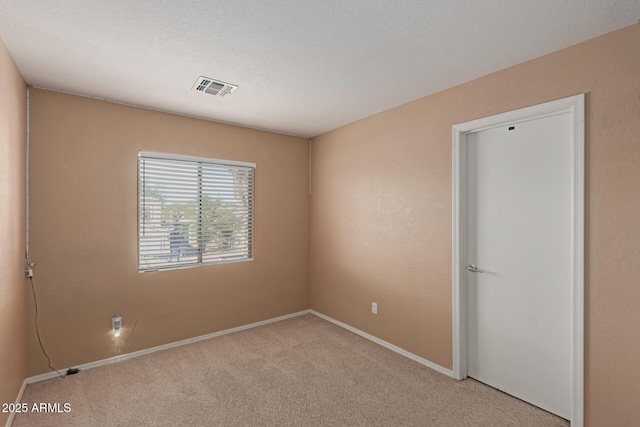 empty room featuring visible vents, baseboards, and light colored carpet