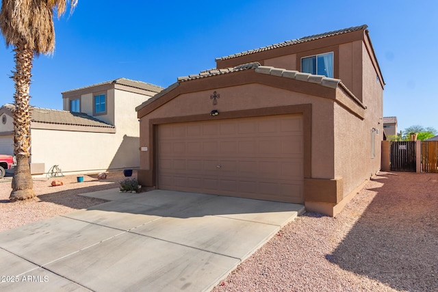 view of front of home featuring concrete driveway, stucco siding, an attached garage, a tiled roof, and fence