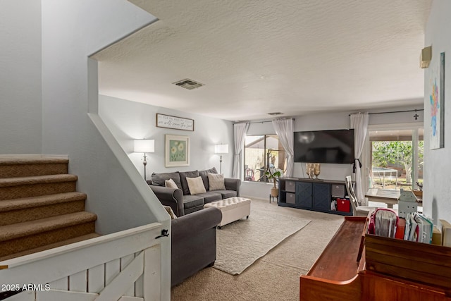 carpeted living room featuring visible vents, stairway, and a textured ceiling