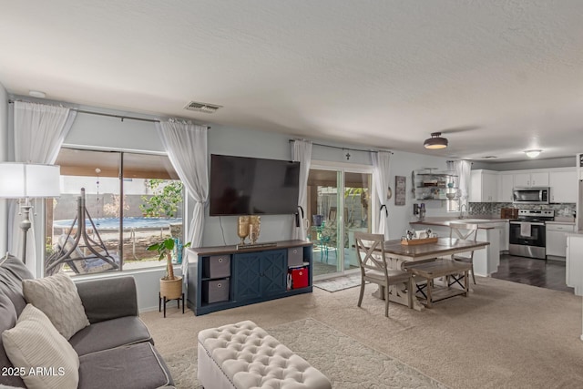 living room featuring a wealth of natural light, visible vents, and a textured ceiling