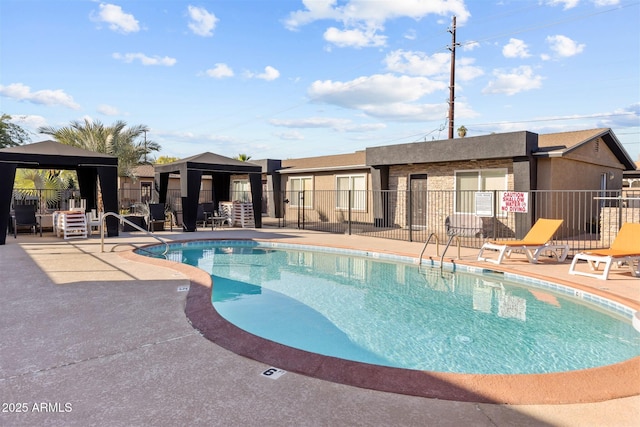 community pool with a gazebo, fence, and a patio area